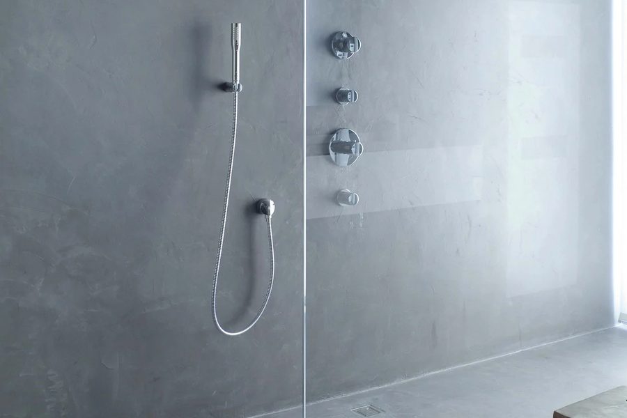 Grey microcement shower with concealed taps, a glass screen and a floor drain