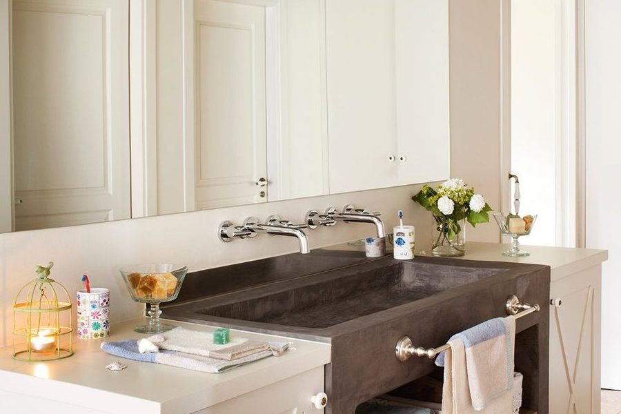 Brown microcement built-in basin beside a light countertop and wall-mounted taps